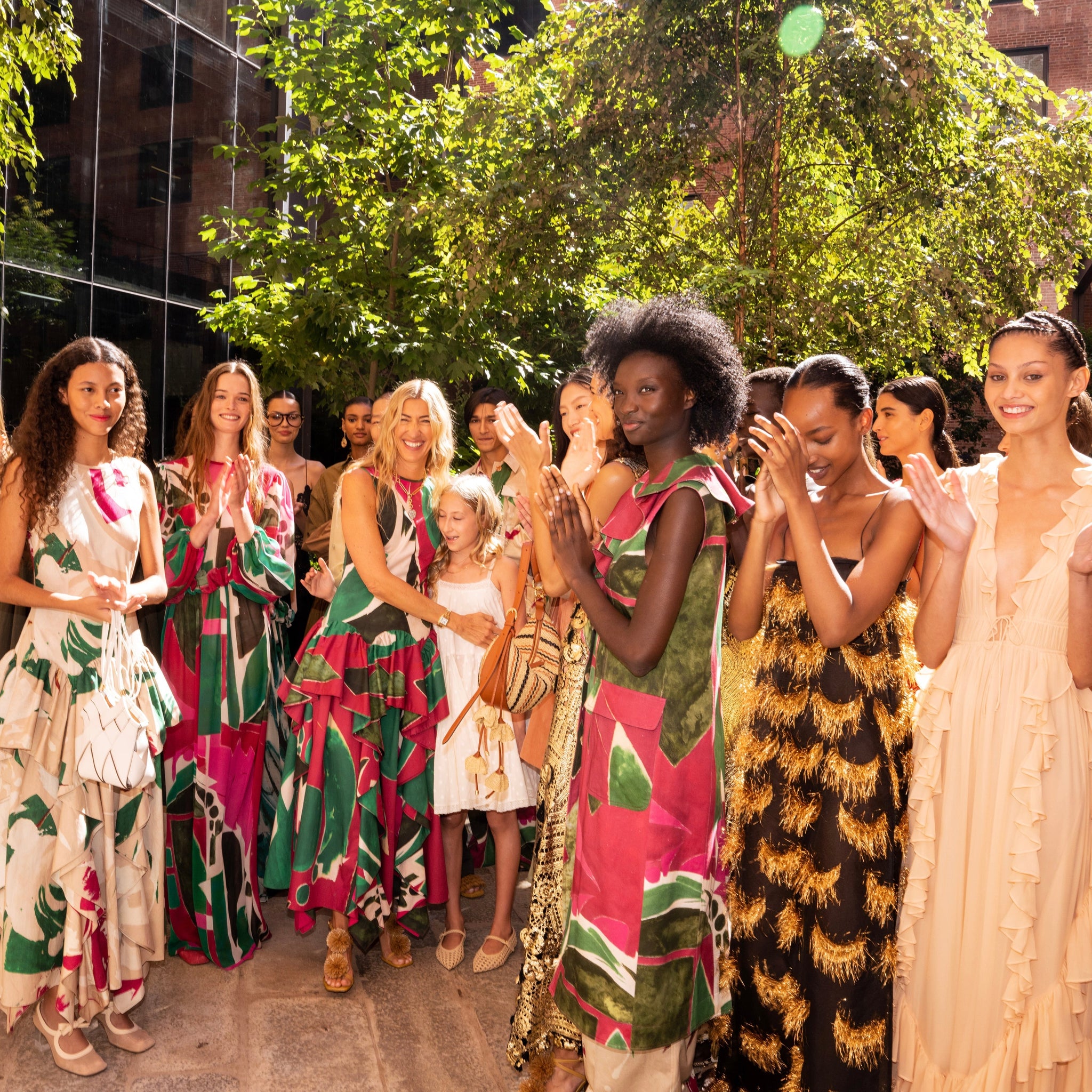 Group of women standing around in long vibrant dresses
